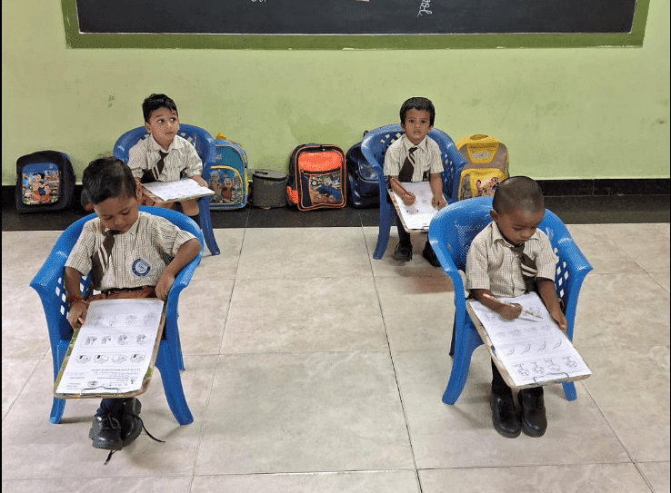 Four children are doing work independently in a classroom.